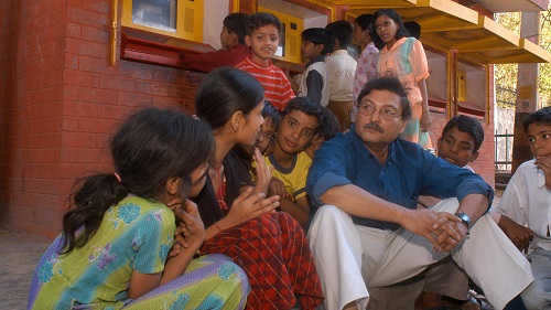 imatge de Sugata Mitra amb alumnes de la barriada de la ciutat de Nova Delhi on va fer l