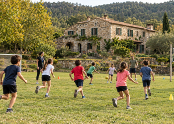 Imagen de una casa de colonias de piedra en la naturaleza con un campo de futbol y juegos de equipo con escolares corriendo juntos